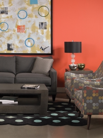 Living room with reddish orange walls, brown sofa, art on the wall with circles and squares