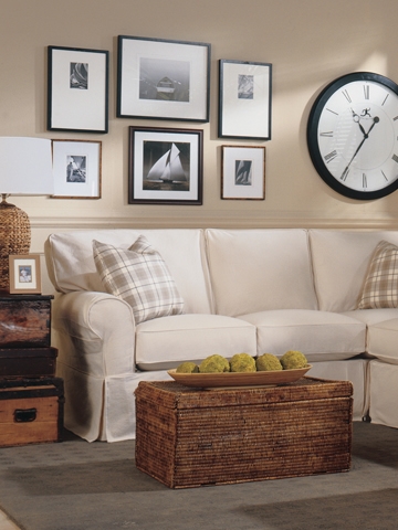 Living room with off white sofa, large clock, sailboat photos.
