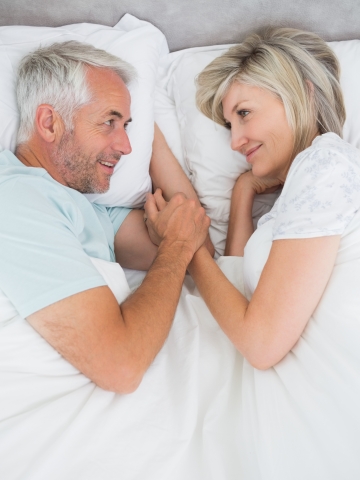 Loving mature man and woman lying in bed